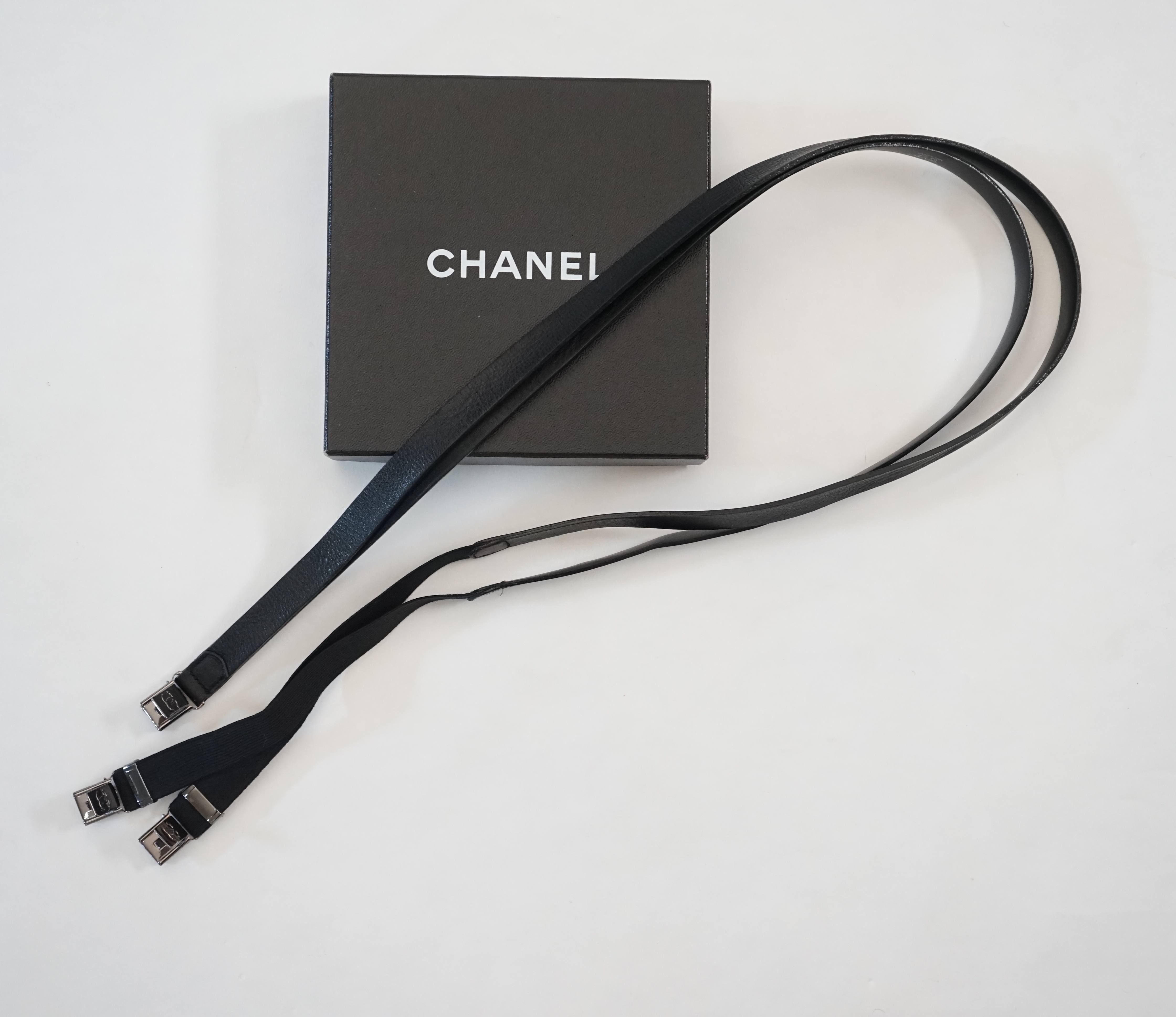 A pair of Chanel black leather one sided braces